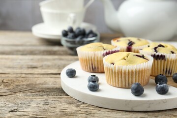Delicious muffins with blueberries on wooden table, closeup. Space for text