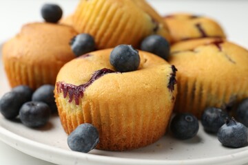 Delicious muffins with blueberries on white table, closeup