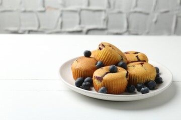 Delicious muffins with blueberries on white wooden table against grey textured background, closeup. Space for text