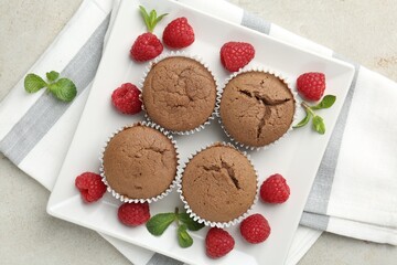 Delicious muffins with raspberries and mint on grey textured table, top view