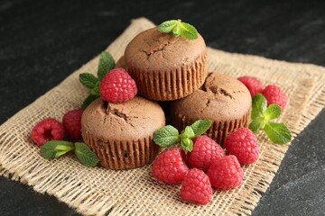 Delicious muffins with raspberries and mint on dark textured table, closeup