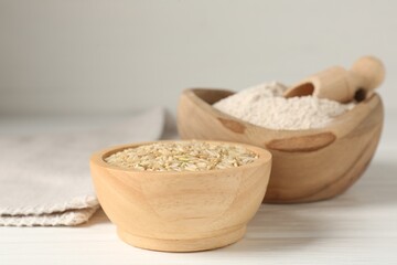 Brown rice and flour on white wooden table, closeup