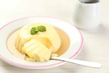 Delicious pudding with caramel sauce and mint served on white table, closeup