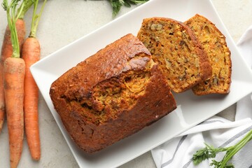 Homemade carrot cake with nuts and vegetables on light grey table, flat lay
