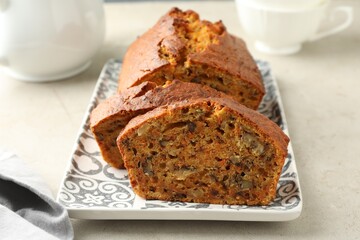 Cut homemade carrot cake with nuts on light grey table, closeup