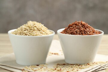 Different types of brown rice in bowls on table, closeup