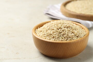 Brown rice in bowl on light grey table, closeup. Space for text