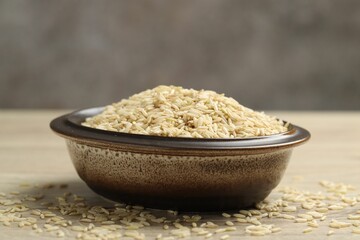 Brown rice in bowl on wooden table, closeup