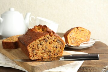 Cut homemade carrot cake with nuts and knife on wooden table, closeup