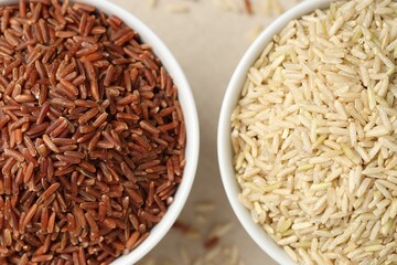 Different types of brown rice in bowls on table, flat lay