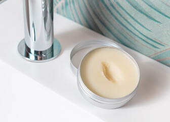 Opened body butter jar on washbasin in green tropical bathroom close up, herbal cosmetic mockup