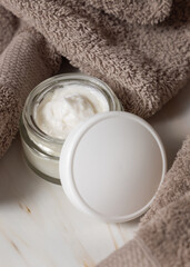 White opened cosmetic jar with white blank lid near light brown towel in bath, packaging mockup