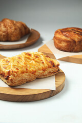 set of three french pastries, on top of a wooden cutting board, on white isolated background