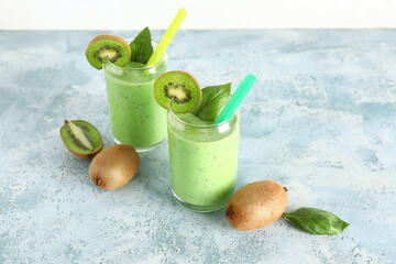 Glasses of fresh kiwi smoothie with basil on blue table