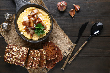Frying pan of tasty banosh with bread on black wooden background