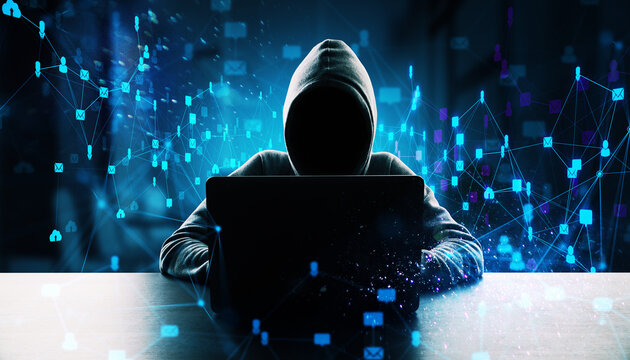 Anonymous hacker in hoodie using laptop at desk.