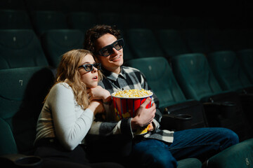 Couple enjoying a movie together while eating popcorn in a cinema
