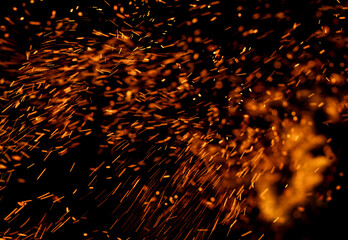 The image is a close up of a fire with a lot of sparks flying out of it