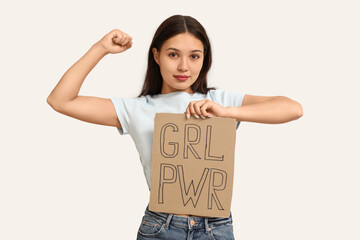Young woman with sign GRL PWR on white background. Feminism concept
