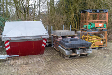Construction materials and dumpster on pallets at building site