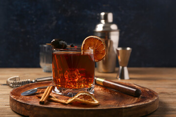 Board with glass of delicious Old Fashioned Cocktail, cinnamon stick, dried orange slices and...