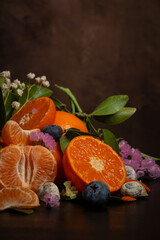 View of half an orange and a tangerine with flowers and leaves, vertically, with copy space