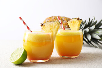 Tasty pineapple cocktail in glasses served on white table