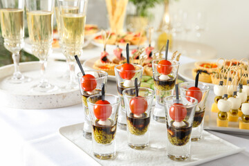 Many different tasty canapes and wine on white table, closeup