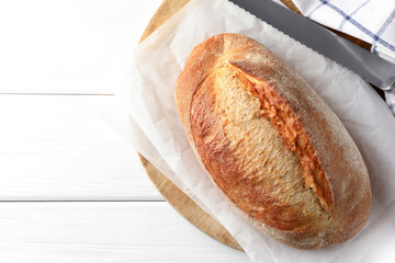 Loaf of delicious bread on white wooden table, top view. Space for text