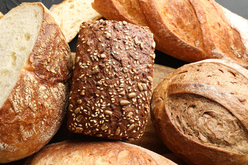 Whole and cut loafs of bread on table, closeup