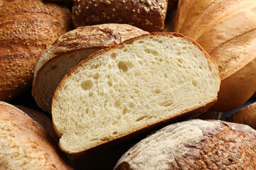 Whole and cut loafs of bread on table, closeup