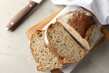 Cut loaf of fresh bread and knife on table, top view