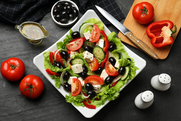 Delicious fresh Greek salad on black table, flat lay