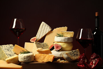 Different types of cheese, rosemary, figs, pomegranate and wine on table