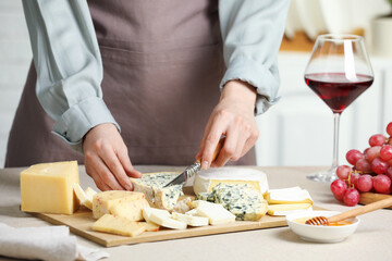 Woman slicing delicious cheese at light textured table indoors, closeup