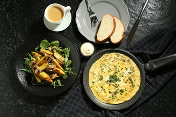 Tasty brunch. Delicious omelette, fried potatoes and coffee served on black textured table, flat lay
