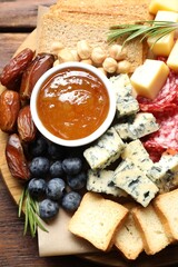 Different types of delicious cheese and other snacks on wooden table, top view