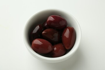 Tasty marinated olives in bowl on white table, closeup