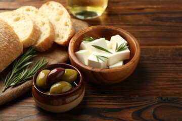 Delicious marinated olives, bread and feta cheese served on wooden table, closeup
