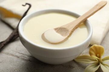 Tasty condensed milk, vanilla pods, flower and spoon on light grey table, closeup