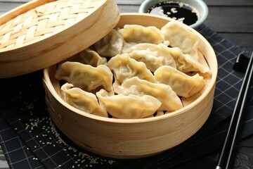 Tasty boiled gyoza (dumplings) served on black table, closeup