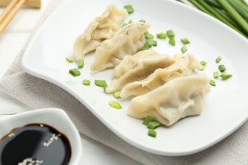 Tasty boiled gyoza (dumplings) served on white wooden table, closeup