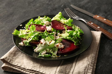 Plate of fresh salad with beet and cottage cheese on black background
