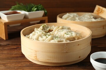 Tasty boiled gyoza (dumplings) in bamboo steamers on wooden table, closeup