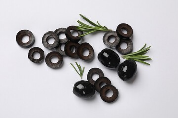 Marinated black olive rings, whole fruits and rosemary on white background, flat lay