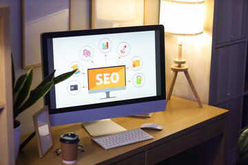 Computer screen with abbreviation SEO in dark office, closeup