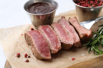 Delicious sliced beef tenderloin with different degrees of doneness, sauce and spices on light table, closeup