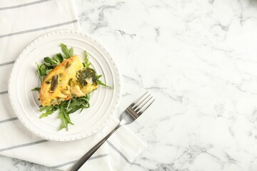Tasty vegetable casserole, arugula and fork on white marble table, top view. Space for text