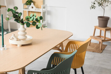 Vase with eucalyptus branches and candles on dining table in room