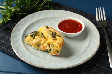 Piece of tasty vegetable casserole and sauce on blue wooden table, closeup
